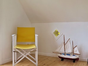 A room with a white folding chair and a small sailboat model. - Delicate Holiday Home in Harboøre near Sea (Harboore)