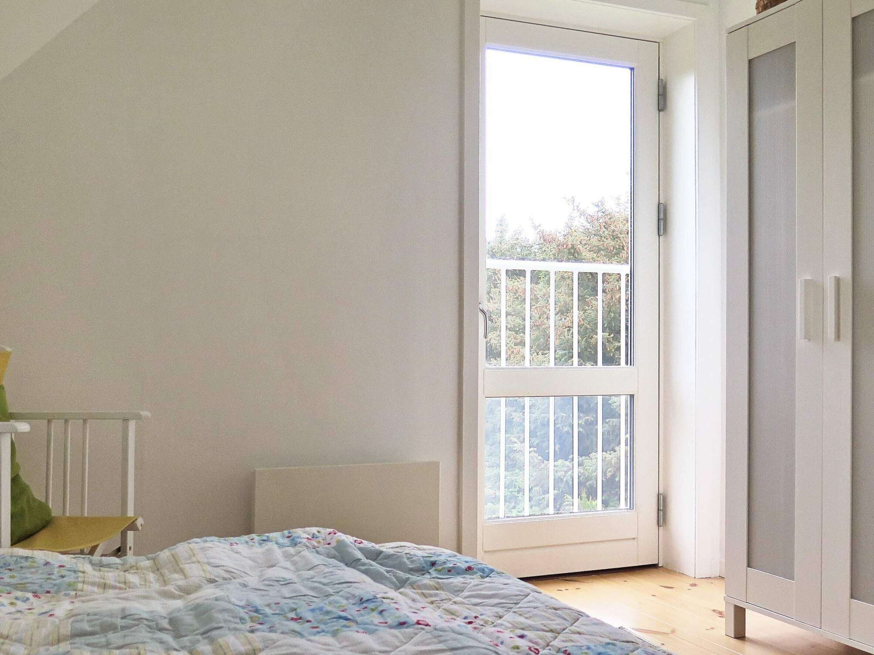 A bedroom with a bed, a window, and a wardrobe.