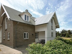 A two-story house with a brick facade, a covered porch, and a small garden area. - Delicate Holiday Home in Harboøre near Sea (Harboore)
