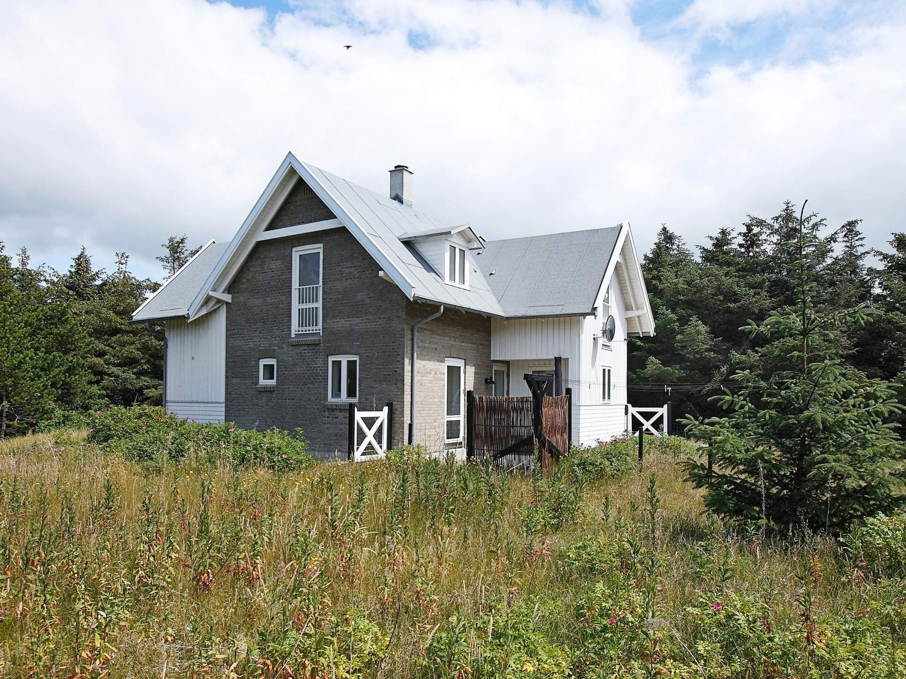 A two-story house with a gabled roof, a chimney, and a fenced yard.