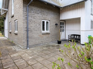 A brick house with a white exterior, a black bench, and a potted plant. - Delicate Holiday Home in Harboøre near Sea (Harboore)