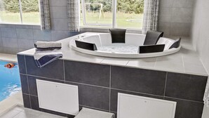 A modern bathroom with a built-in bathtub, a small step leading to the pool, and a view of the outdoors. - 5 Star Holiday Home in Vaeggerlose (Vaeggerlose)