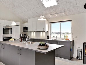 A modern kitchen with a central island, stainless steel appliances, and a large window providing a view.