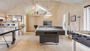 A pool table in a room with wooden walls and ceiling, a bar area, and a television mounted on the wall. - 5 Star Holiday Home in Vaeggerlose (Vaeggerlose)