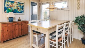 A dining area with a wooden table, white chairs, a hanging light fixture, and a painting on the wall. - Spacious Holiday Home in KarrebÃ¦ksminde near Fishing (Karrebæksminde)