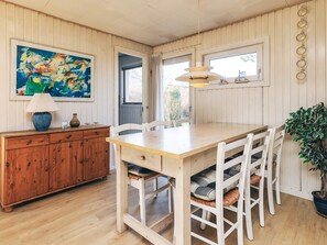 A dining area with a wooden table, white chairs, a hanging light fixture, and a painting on the wall. - Spacious Holiday Home in KarrebÃ¦ksminde near Fishing (Karrebæksminde)