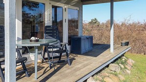 Uma área externa coberta com mesa e cadeiras, um armário azul e vista para a paisagem ao redor.
