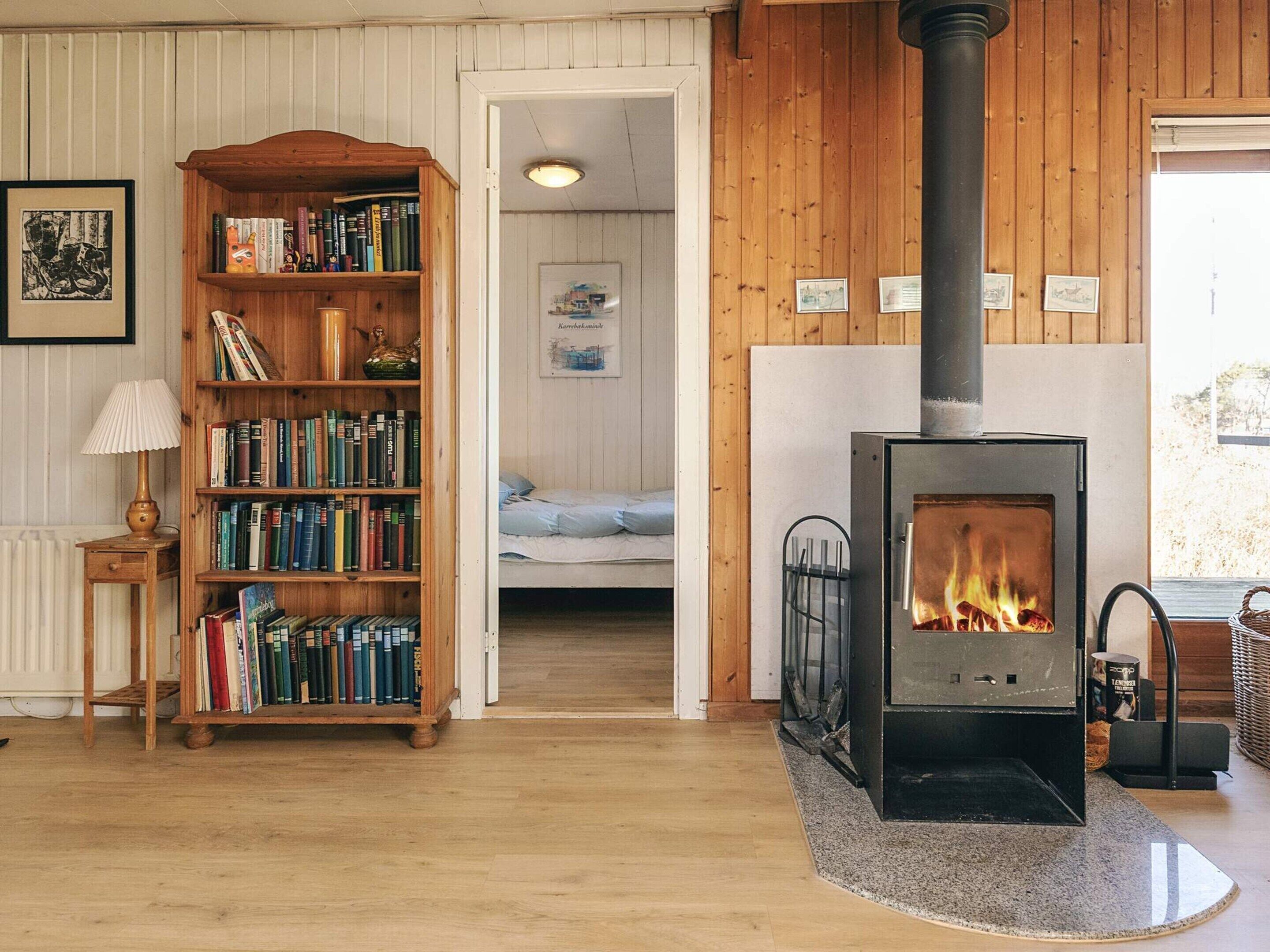 A cozy room with a wooden bookshelf, a fireplace, and a bed.