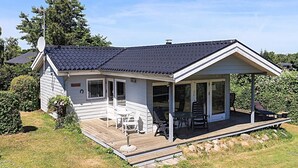 Uma casa térrea com varanda coberta, antena parabólica e um pequeno deck.