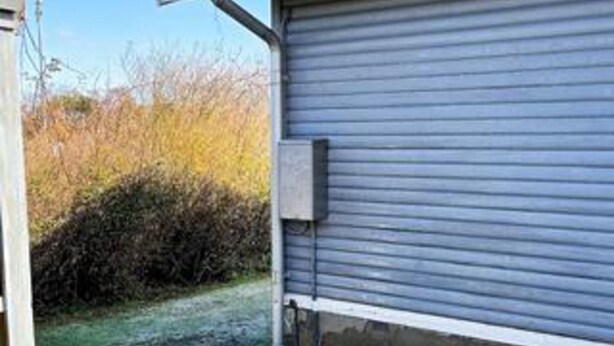 Portão de garagem fechado com uma caixa de serviços na parede.
