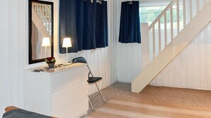 A room with a white dresser, a chair, a desk with a lamp, a mirror, and a staircase. - 6 Person Holiday Home in Sæbø (Orsta)