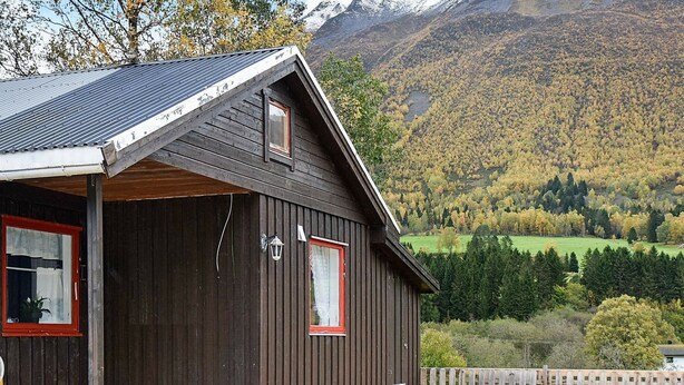 A wooden cabin with a sloped roof, a porch, and a view of a mountainous landscape. - 6 Person Holiday Home in Sæbø (Orsta)