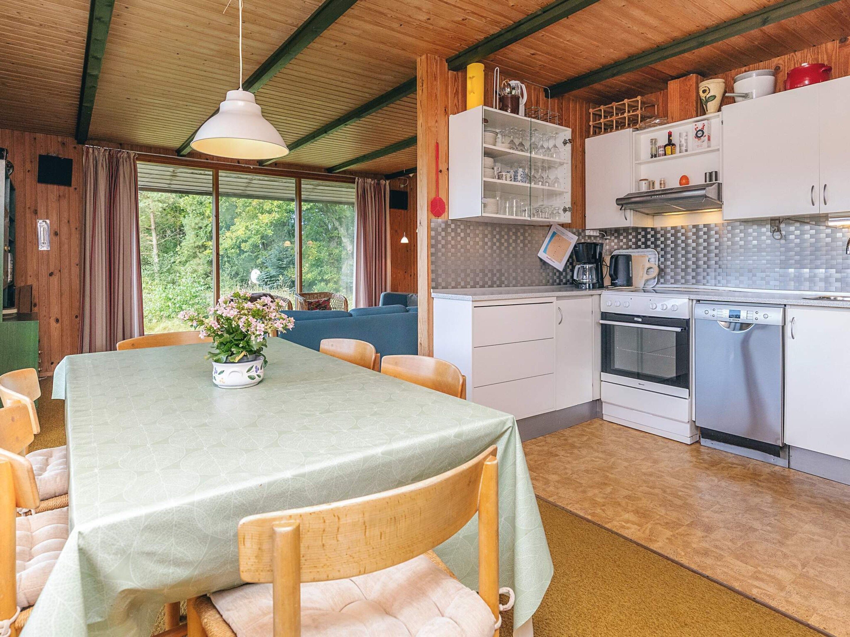 Cozinha acolhedora com armários de madeira, uma mesa de jantar e vista para o verde lá fora.