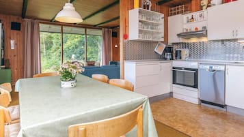 Cozinha acolhedora com armários de madeira, uma mesa de jantar e vista para o verde lá fora.
