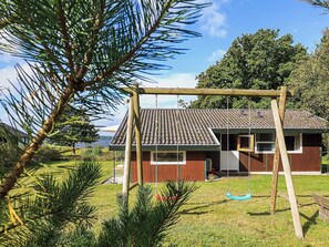 Una casa con techo de tejas, un columpio y vista a un lago.