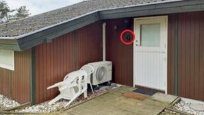 A building with a red door, an air conditioning unit, and a white chair outside. - 8 Person Holiday Home in Skals (Skals)