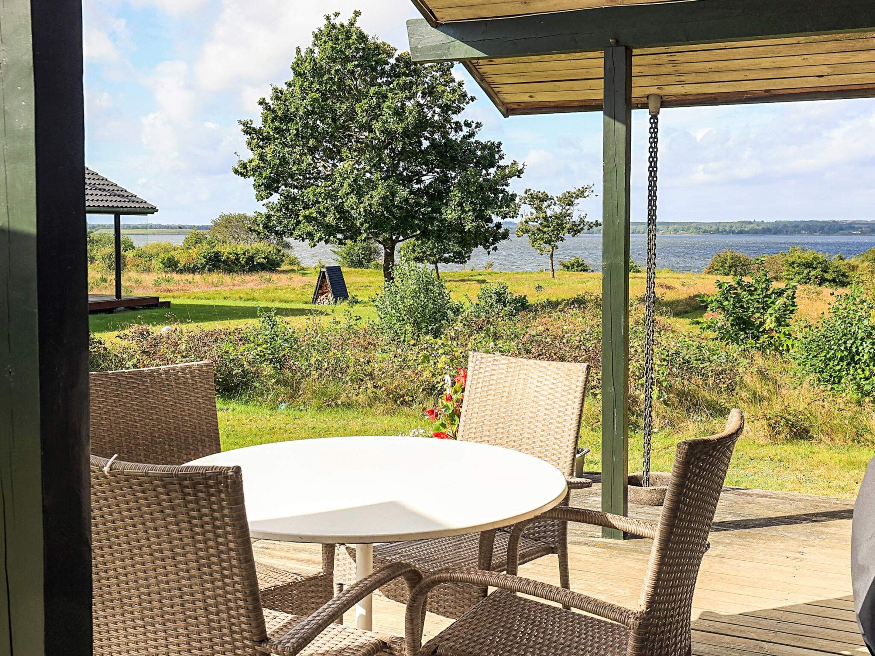 An outdoor seating area with wicker furniture and a view of a lake.