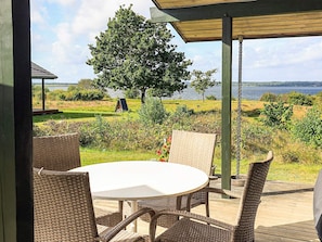 Un espace extérieur aménagé avec des meubles en osier et offrant une vue sur un lac.