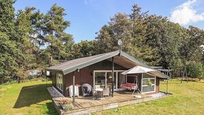 A wooden cabin with a porch, a swing, and a covered seating area. - 8 Person Holiday Home in Skals (Skals)