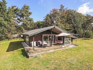 A wooden cabin with a porch, a swing, and a covered seating area.