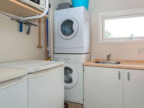 A compact laundry room with a front-loading washing machine, a dryer, and a sink. - Spacious Holiday Home in Hemmet near Sea (Hemmet)