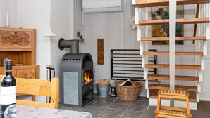 A cozy room with a fireplace, wooden furniture, a ladder, and a wall-mounted air conditioning unit. - Spacious Holiday Home in Hemmet near Sea (Hemmet)