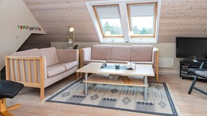 A cozy loft-style room with a wooden ceiling, a sofa, a coffee table, a TV, and a small desk. - Spacious Holiday Home in Hemmet near Sea (Hemmet)