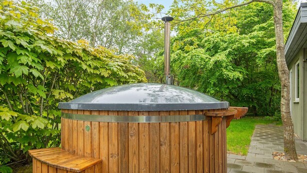 A wooden hot tub with a metal roof and steps leading up to it, surrounded by lush greenery. - Spacious Holiday Home in Hemmet near Sea (Hemmet)