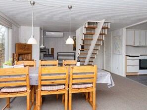 A dining area with a wooden table and chairs, a staircase, and a kitchen area. - Spacious Holiday Home in Hemmet near Sea (Hemmet)