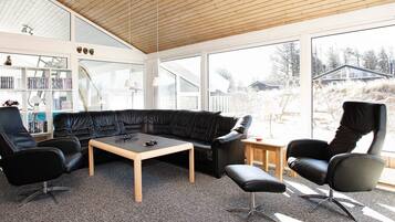 Ett modernt vardagsrum med en svart lädersoffa, ett soffbord i trä och svarta läderstolar.