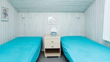 Ett rum med två separata sängar, ett nattduksbord med en lampa och en tavla som hänger på väggen.