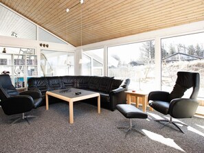 A modern living room with a black leather sofa, a wooden coffee table, and black leather chairs.