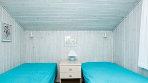 A room with two single beds, a nightstand with a lamp, and a wall-mounted picture. - 5 Star Holiday Home in Blokhus (Blokhus)