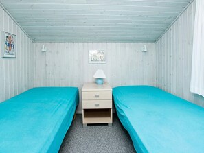A room with two single beds, a nightstand with a lamp, and a wall-mounted picture. - 5 Star Holiday Home in Blokhus (Blokhus)
