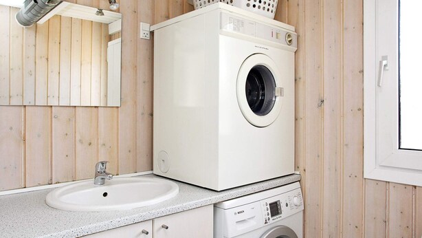 A compact laundry room with a washing machine, a sink, and a mirror. - 5 Star Holiday Home in Blokhus (Blokhus)