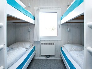 A bunk bed room with a window, a heater, and a wall-mounted light fixture.
