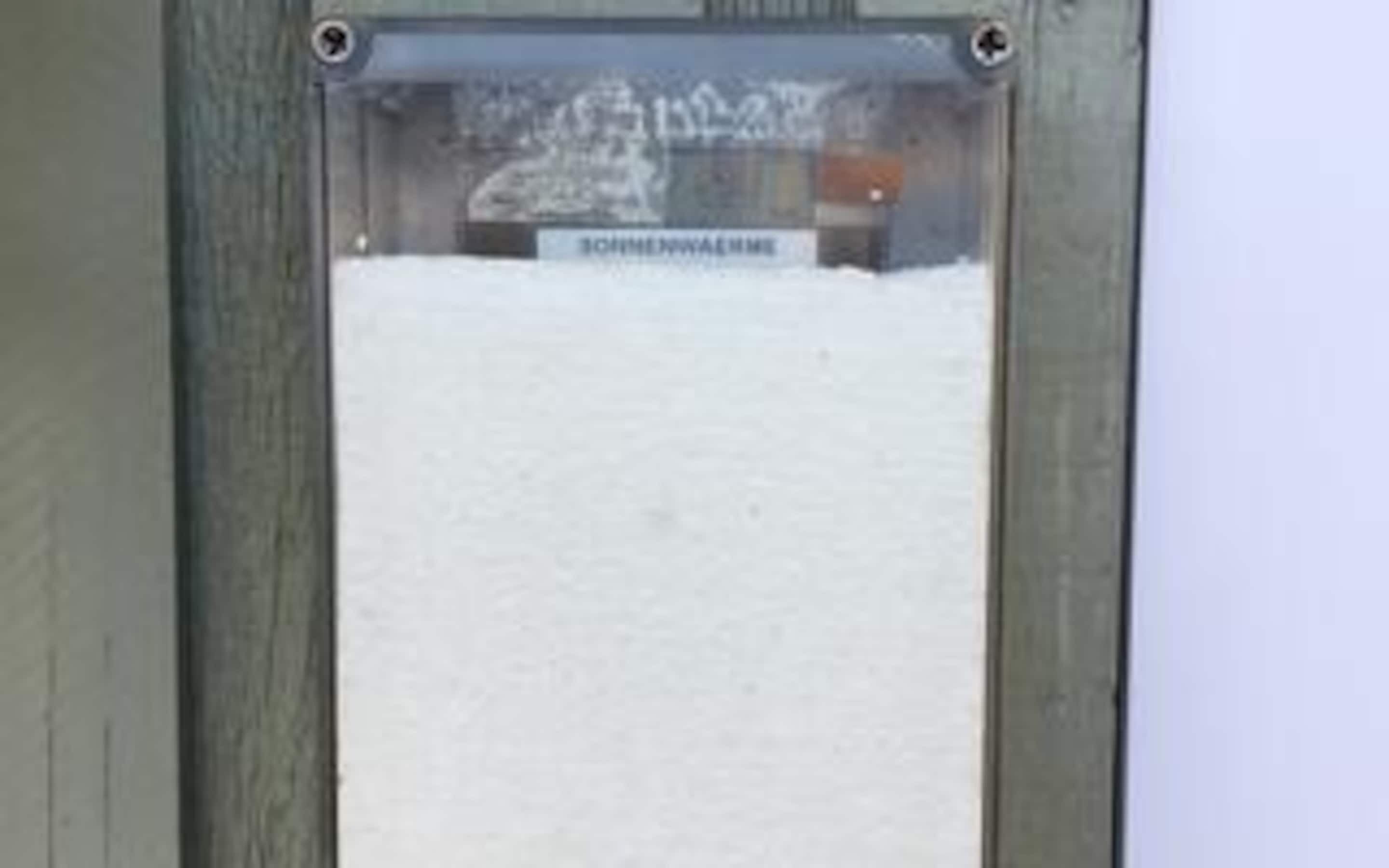 Ein mit Schnee bedecktes Fenster mit einem Schild, auf dem 'SOMMERHAUS' steht.