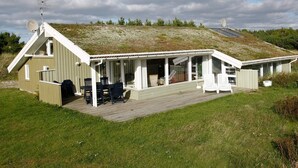 A single-story building with a sloped roof, a covered patio area with outdoor seating, and a satellite dish on the roof. - 5 Star Holiday Home in Blokhus (Blokhus)