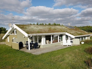 A single-story building with a sloped roof, a covered patio area with outdoor seating, and a satellite dish on the roof. - 5 Star Holiday Home in Blokhus (Blokhus)