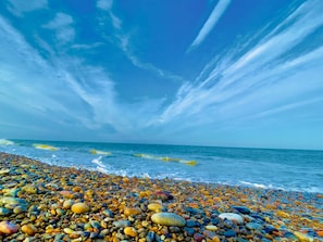 Ein Kiesstrand mit Blick auf den Ozean und einem klaren Himmel.