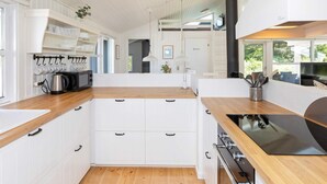 Cozinha moderna com armários brancos, bancada de madeira e fogão preto.