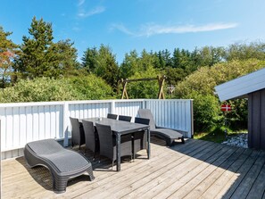 An outdoor deck with a table and chairs, surrounded by a white fence and greenery. - 5 Star Holiday Home in Fjerritslev (Fjerritslev)