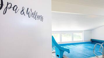 An indoor swimming pool with a blue chair and a sign reading 'Spa & Wellness'.