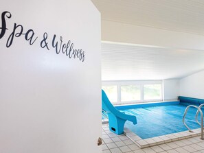Une piscine intérieure avec une chaise bleue et un panneau indiquant « Spa et bien-être ».