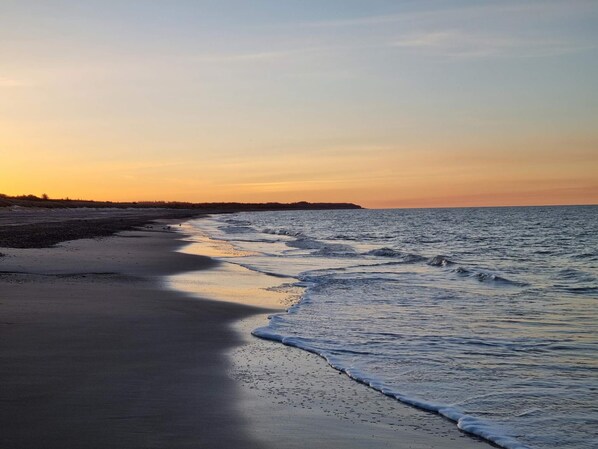 Une plage avec une mer calme et un ciel dégagé.