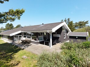 A modern building with a covered patio area, large windows, and a deck.