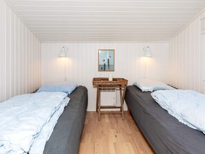 A room with two beds, a small table, and a wall-mounted picture.