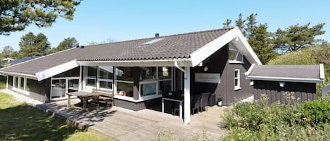 A modern building with a covered patio area, large windows, and a deck.