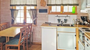 A compact kitchen with a wooden table and chairs, a small refrigerator, and basic appliances. - 6 Person Holiday Home in Nordli (Lierne)