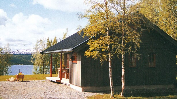 A wooden cabin with a porch, a small deck, and a gravel driveway. - 6 Person Holiday Home in Nordli (Lierne)